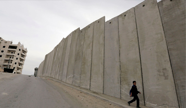 A Palestinian boy walks past a section of the controversial Israeli barrier, in Shuafat refugee camp in the West Bank near Jerusalem November 23, 2013. Marooned behind the wall, Israel's controversial barrier, the Shuafat refugee camp reveals the state's uneven treatment of Arab and Jewish neighbourhoods, creating a de facto partition of Jerusalem, which is the epicentre of the Middle East conflict. Picture taken November 23, 2013. (REUTERS/Ammar Awad) - via Baltimore Sun click for link